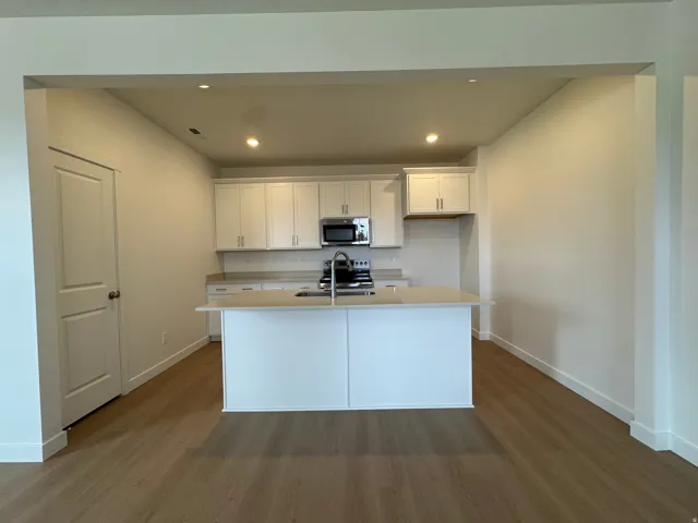 Kitchen with white cabinetry, dark wood-type flooring, recessed lighting, a kitchen island with sink, and stainless steel appliances