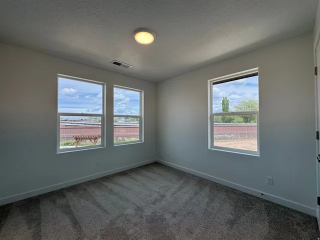 Unfurnished room featuring dark carpet and a textured ceiling