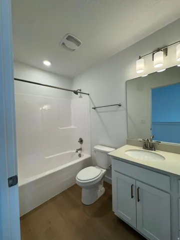 Bathroom with vanity, dark wood-type flooring, shower / bath combination, and a textured ceiling