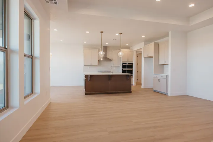 Kitchen featuring light wood-type flooring, open floor plan, a kitchen bar, a center island with sink, and dual tone cabinets