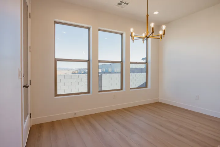Empty room featuring a chandelier and light wood-style flooring