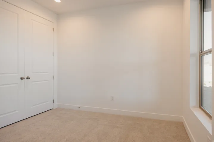 Unfurnished bedroom with a closet, light colored carpet, and recessed lighting