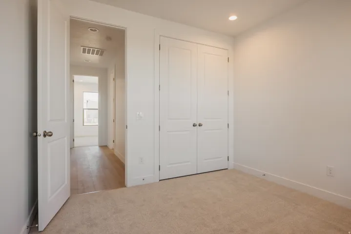 Unfurnished bedroom with light colored carpet, a closet, and recessed lighting