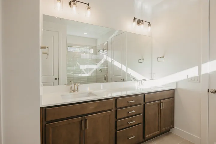 Bathroom featuring double vanity, a stall shower, and light tile patterned floors