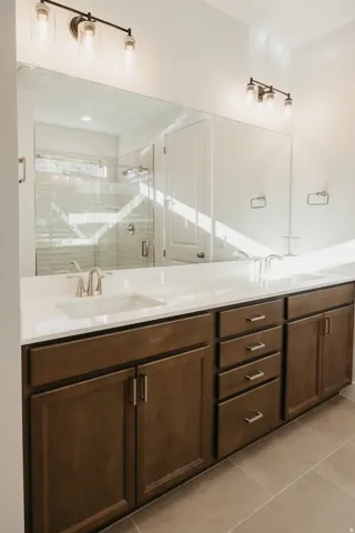 Full bath featuring double vanity, a shower stall, and light tile patterned floors