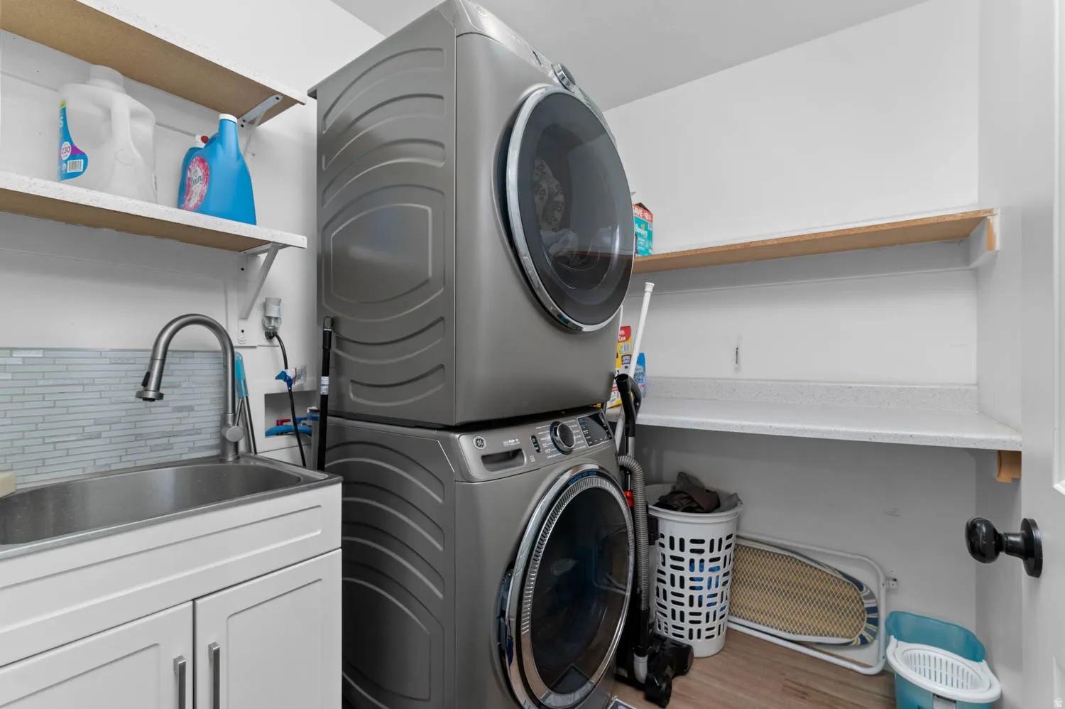 Laundry room with stacked washer / drying machine and light wood-style flooring