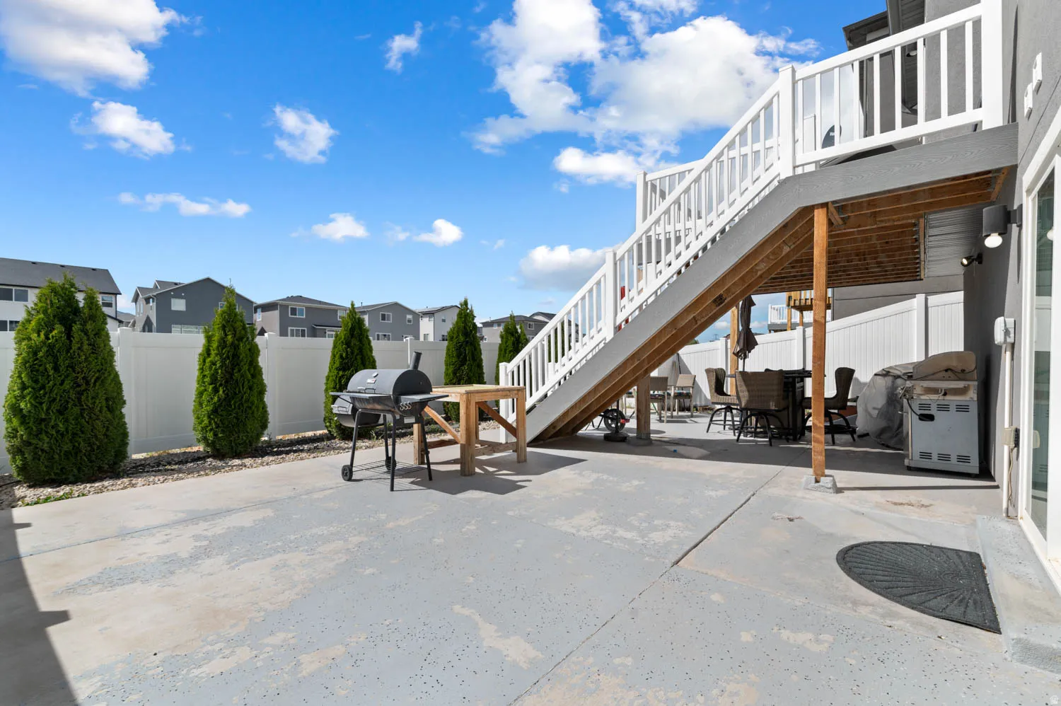 Fenced backyard with a residential view, outdoor dining area, area for grilling, a patio area, and a wooden deck