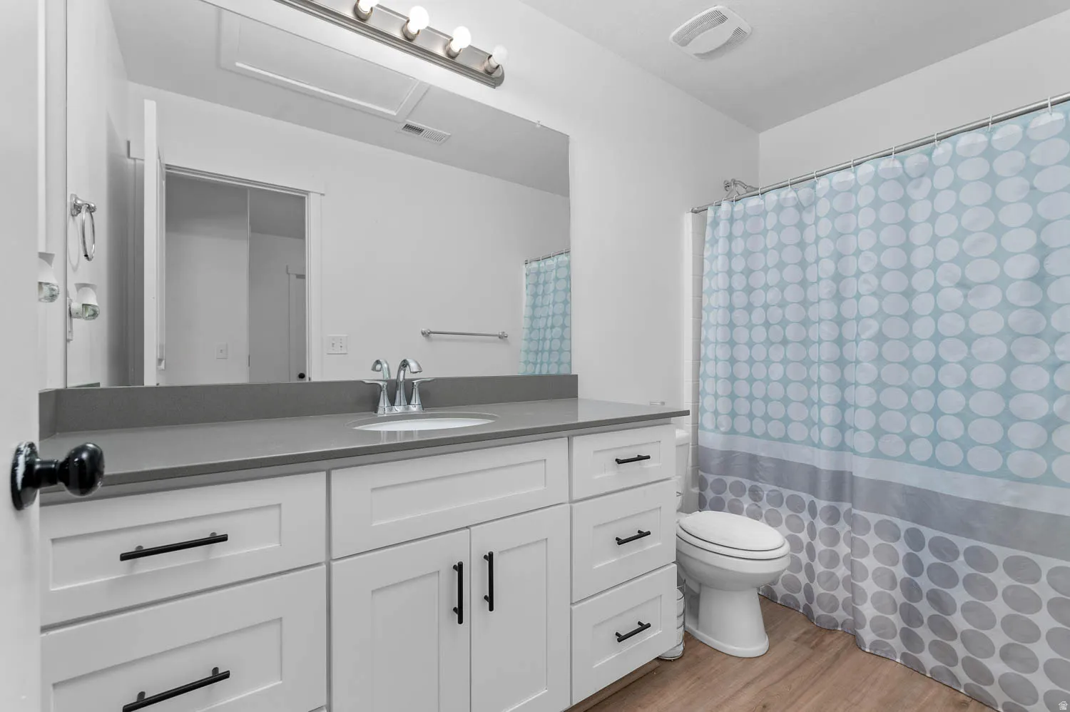 Full bathroom with vanity, a shower with curtain, and light wood finished floors