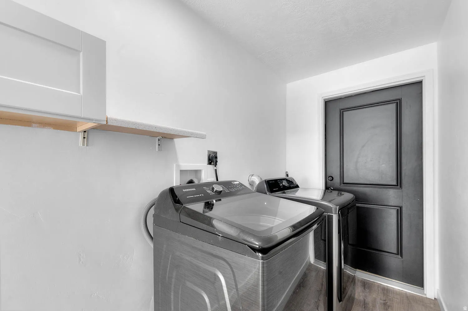 Laundry area with separate washer and dryer and wood finished floors