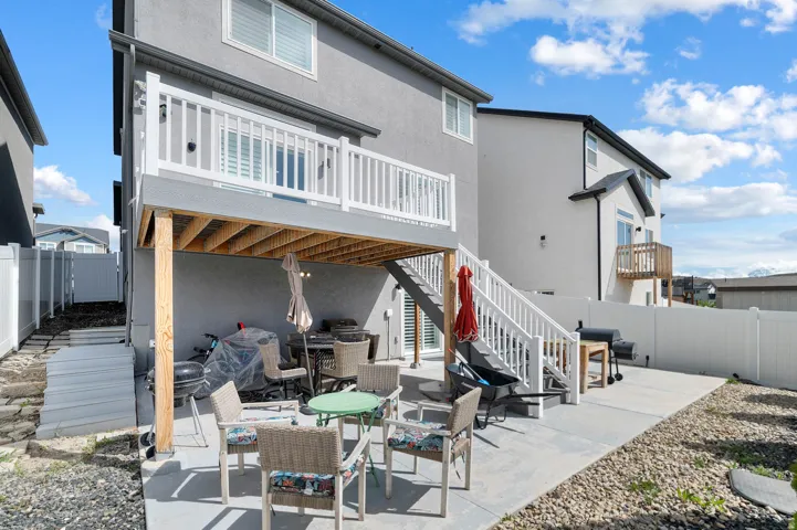 Rear view of house featuring a fenced backyard, a patio, stucco siding, and outdoor dining area
