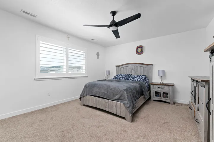 Bedroom with a ceiling fan and light colored carpet
