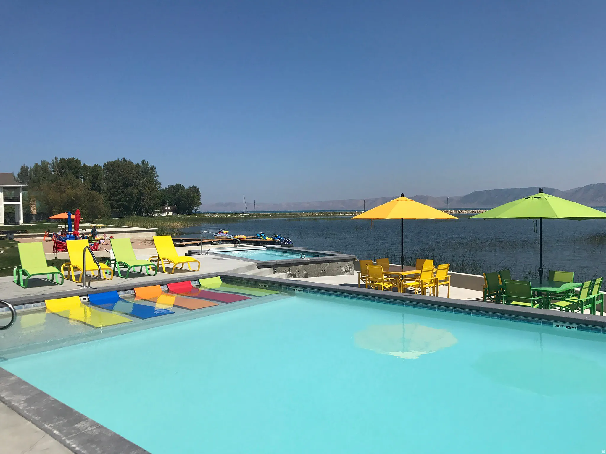 Community pool with outdoor dining space, a water view, and a jacuzzi