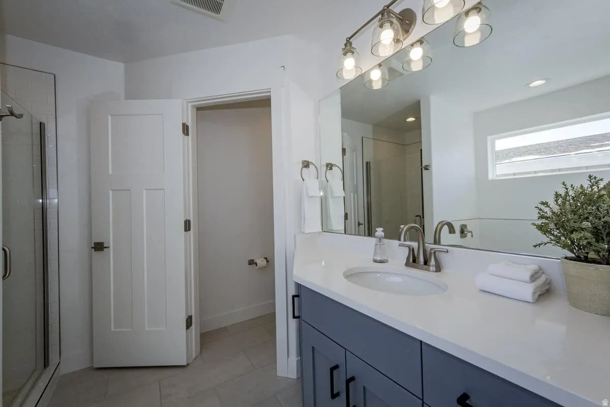 Full bathroom featuring a shower stall, vanity, light tile patterned floors, and recessed lighting