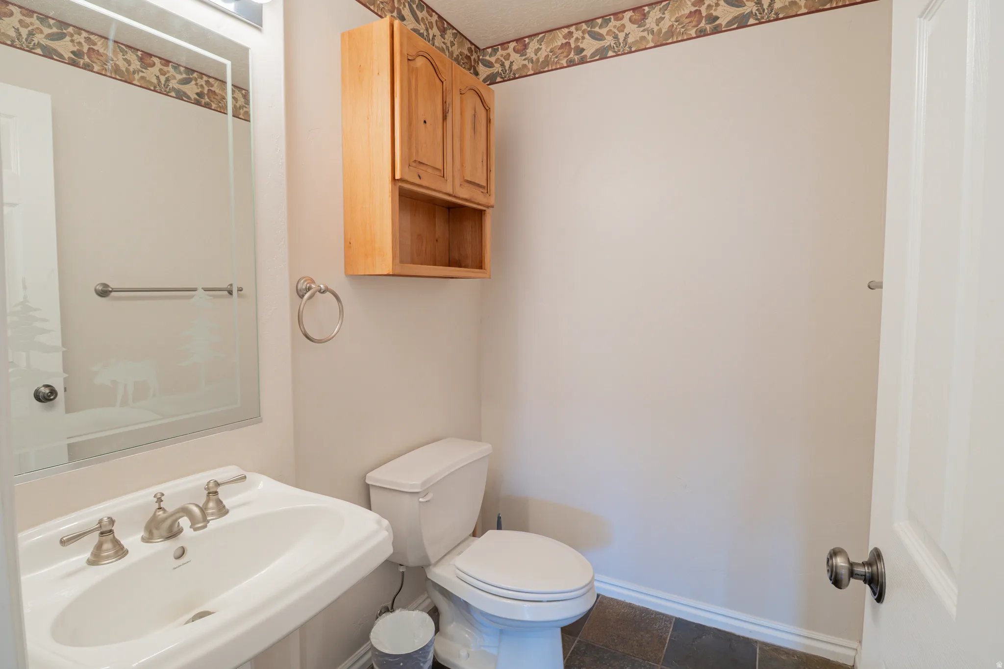 Half bathroom with toilet and dark stone finish flooring