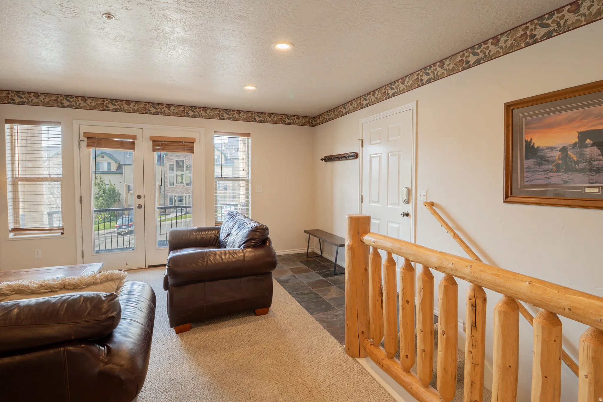 Carpeted living room with a textured ceiling, french doors, stone finish floors, and recessed lighting