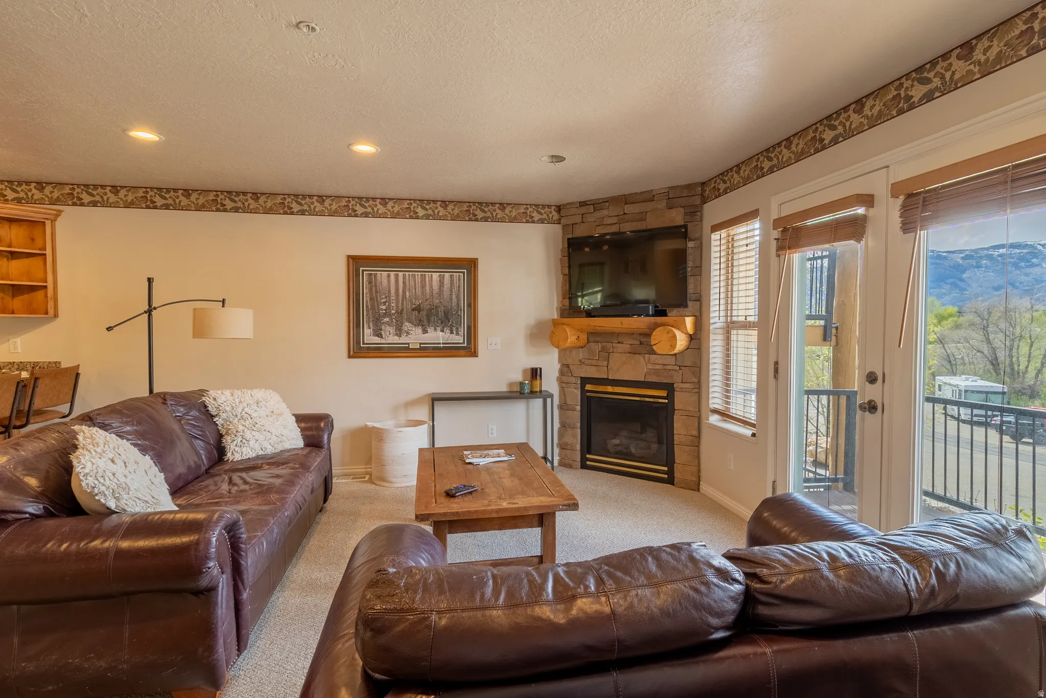Living area featuring light colored carpet, a fireplace, and a textured ceiling