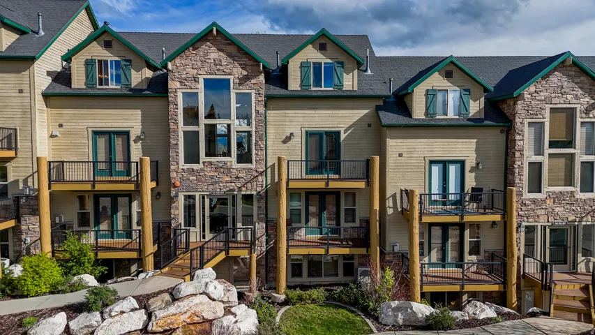 Rear view of house with a balcony, french doors, stone siding, and a residential view