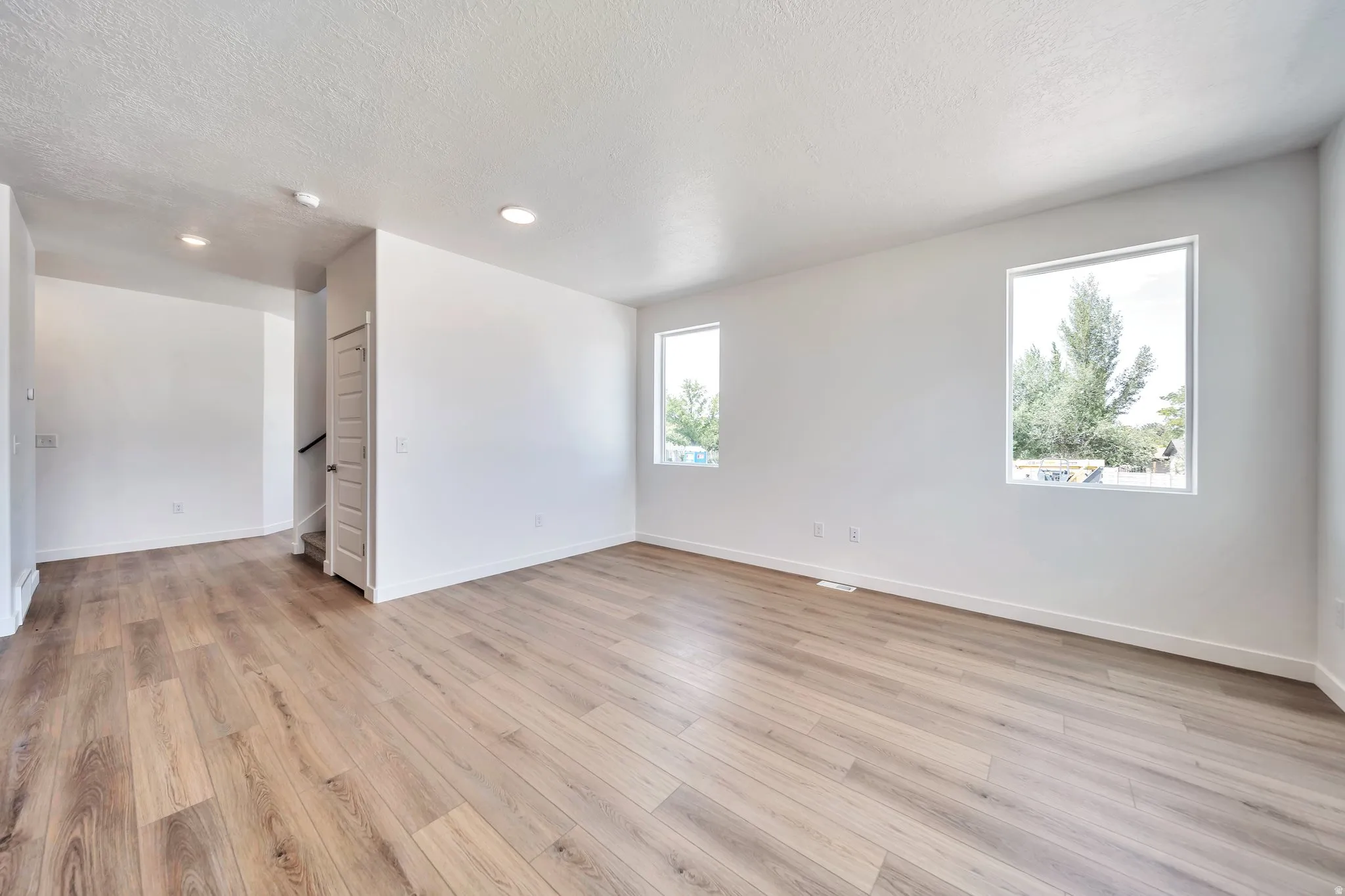 Unfurnished room featuring a textured ceiling, light wood-style flooring, and recessed lighting