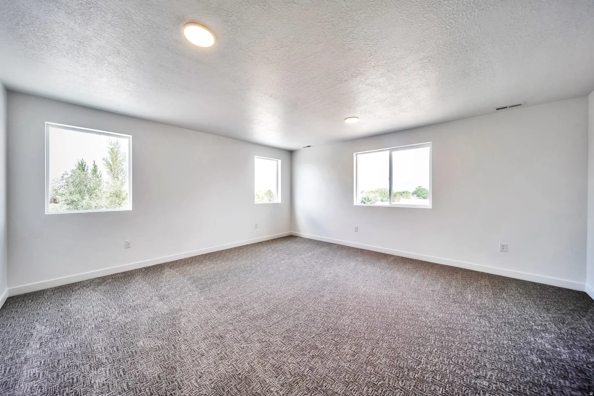 Empty room with a textured ceiling and carpet flooring