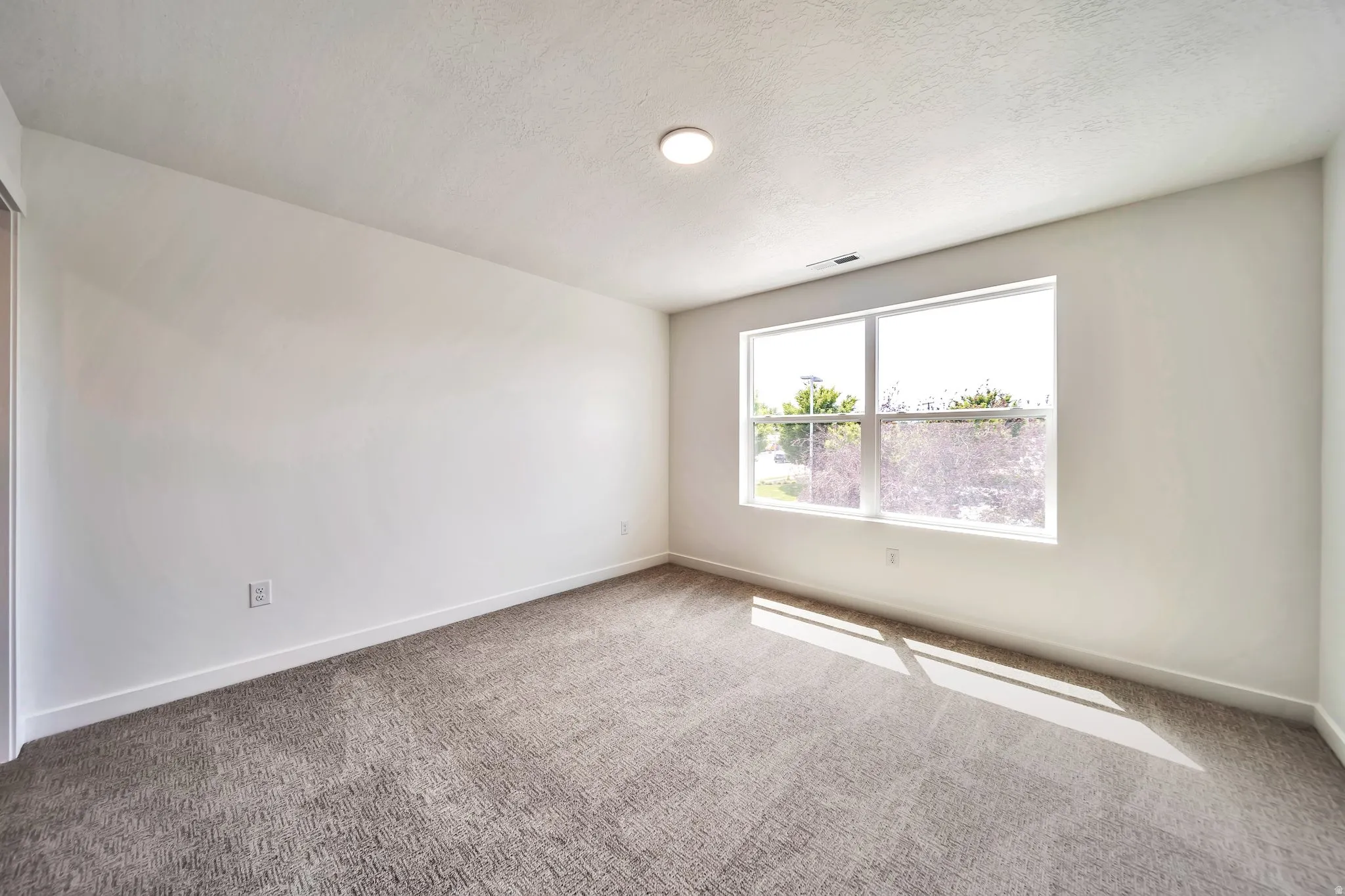 Carpeted spare room featuring baseboards and a textured ceiling
