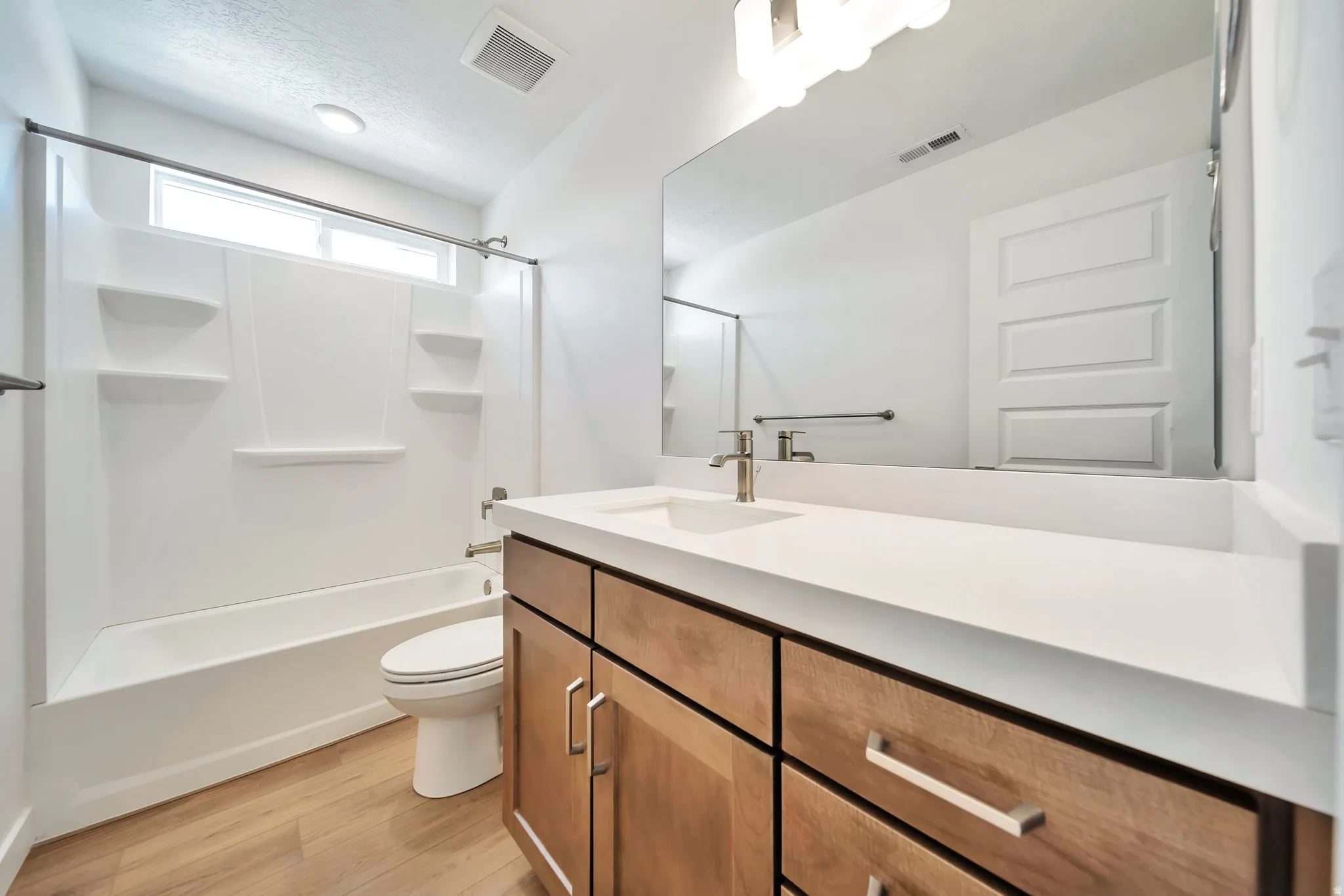Bathroom with vanity, light wood-style floors, and shower / tub combination