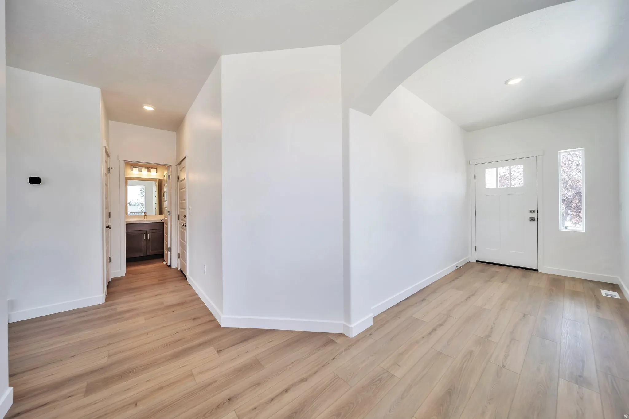 Foyer entrance featuring light wood-type flooring, arched walkways, and recessed lighting