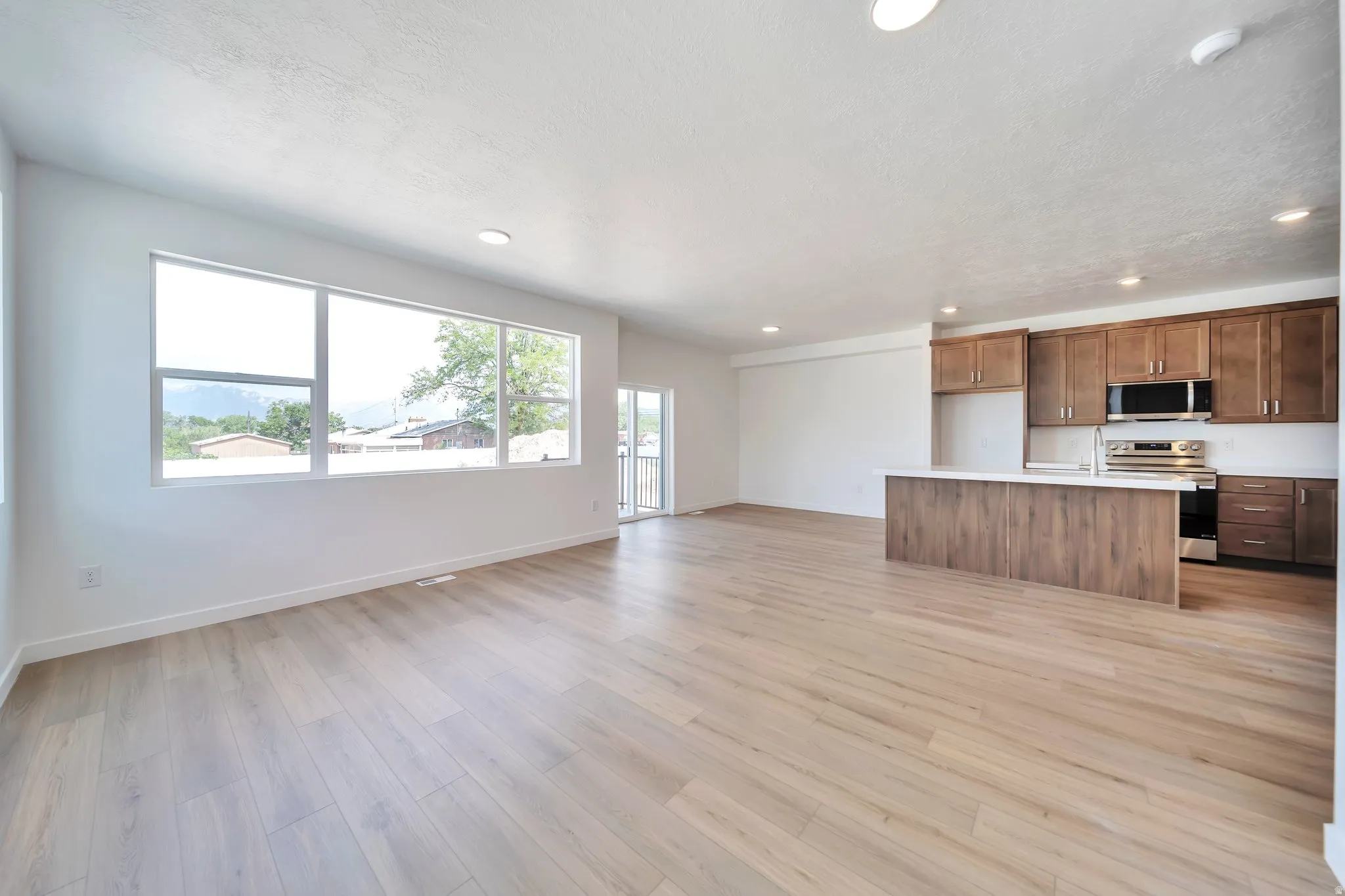 Unfurnished living room featuring light wood-type flooring, recessed lighting, and a textured ceiling