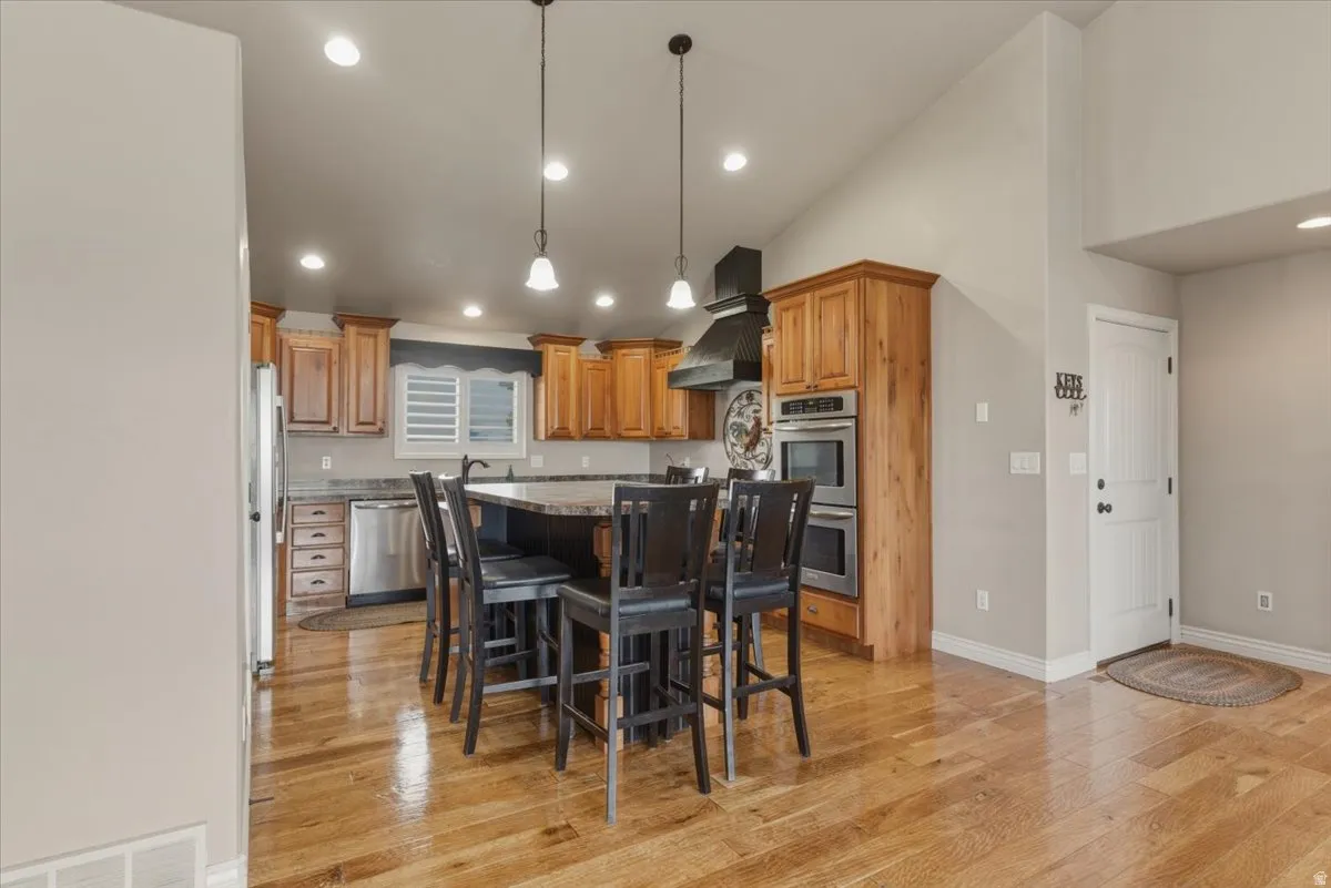 Kitchen featuring a kitchen island, a kitchen breakfast bar, hanging light fixtures, light wood-style floors, and wood finish cabinetry