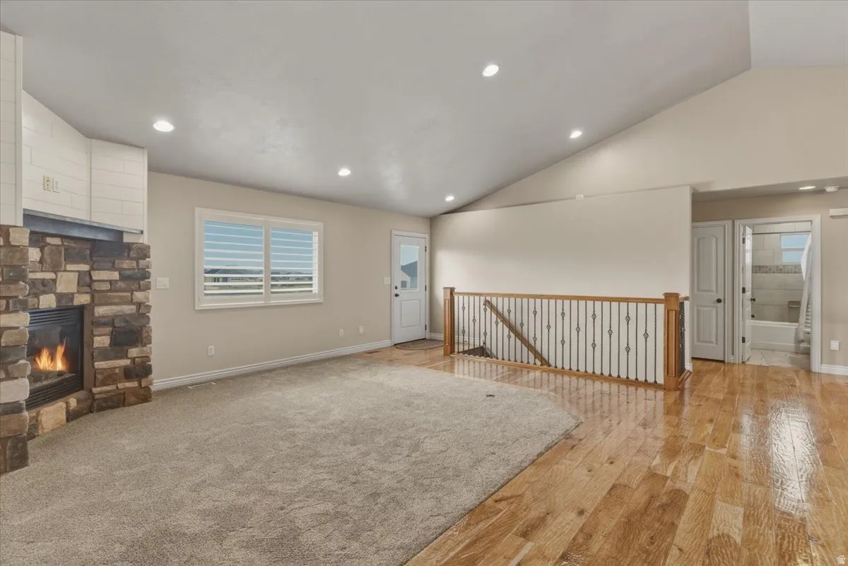 Unfurnished living room with a fireplace, light wood finished floors, recessed lighting, and vaulted ceiling