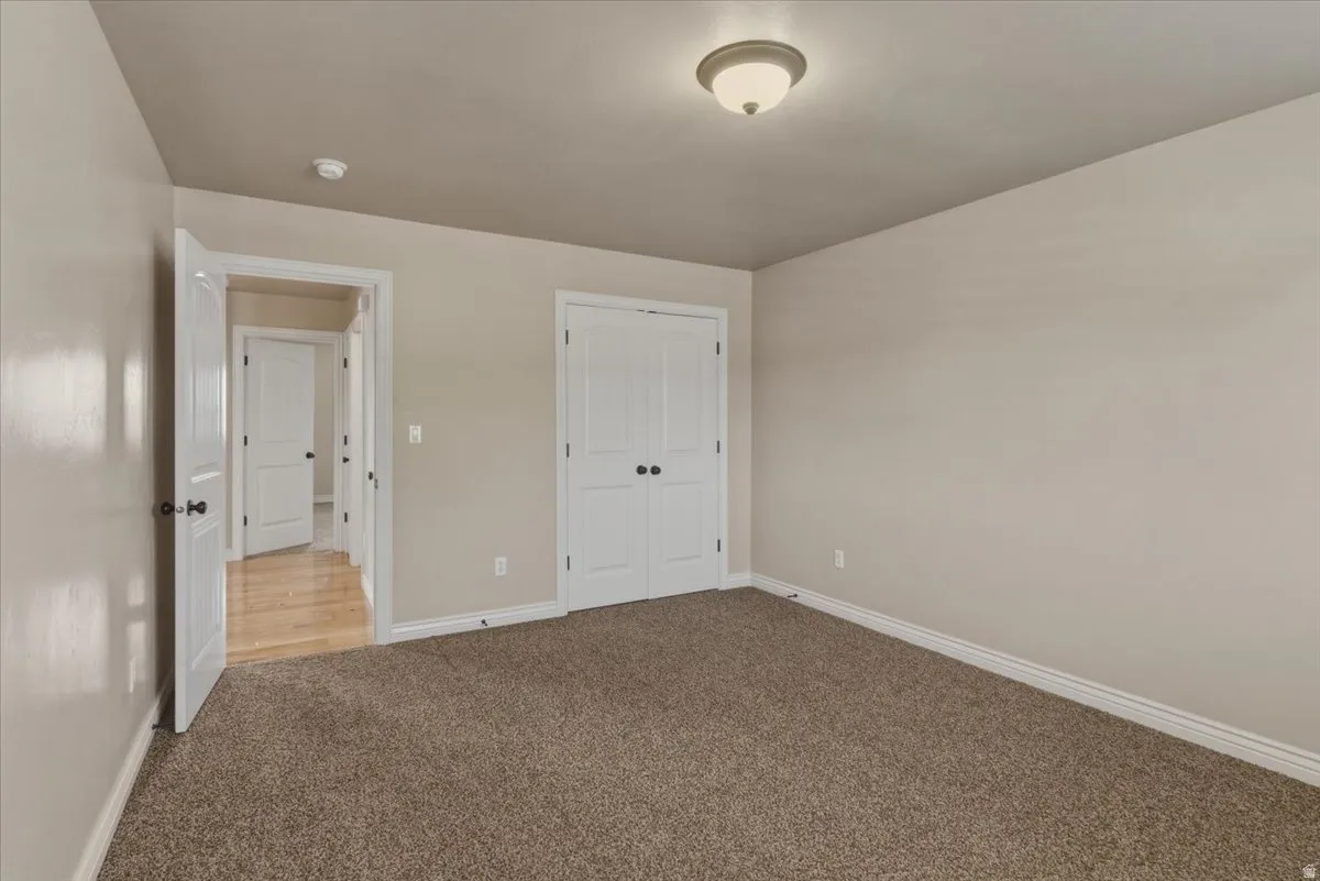Unfurnished bedroom featuring light carpet and a closet