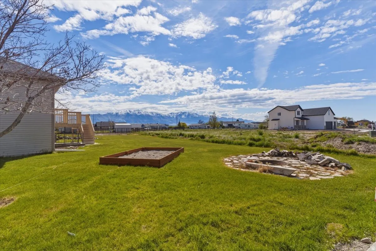 View of green lawn with a deck with mountain view and a vegetable garden