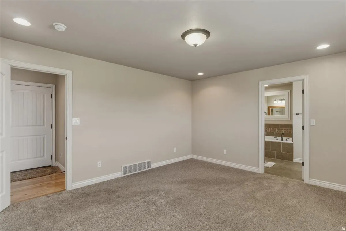 Unfurnished bedroom featuring light carpet, recessed lighting, and connected bathroom