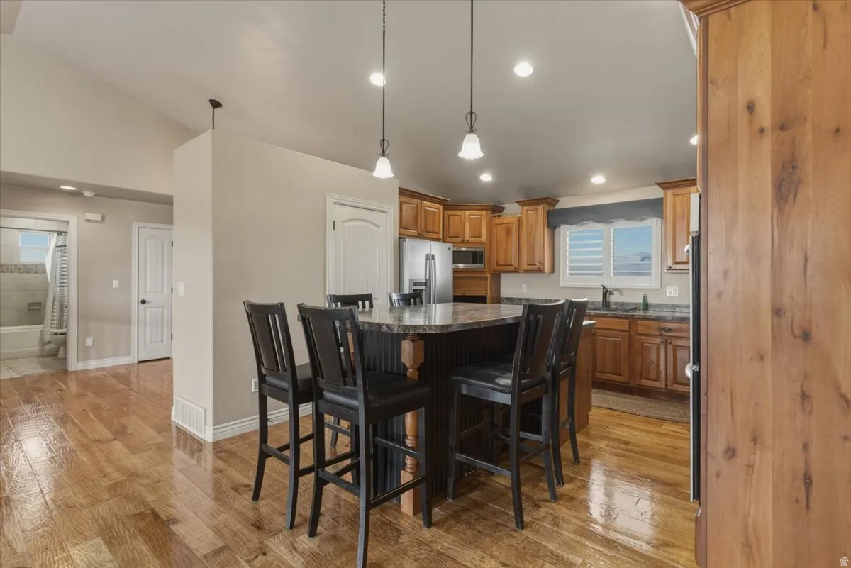 Kitchen featuring a kitchen bar, a kitchen island, stainless steel appliances, pendant lighting, and light wood-style floors