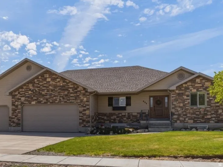 Single story home with a garage, covered porch, stone siding, driveway, and a shingled roof