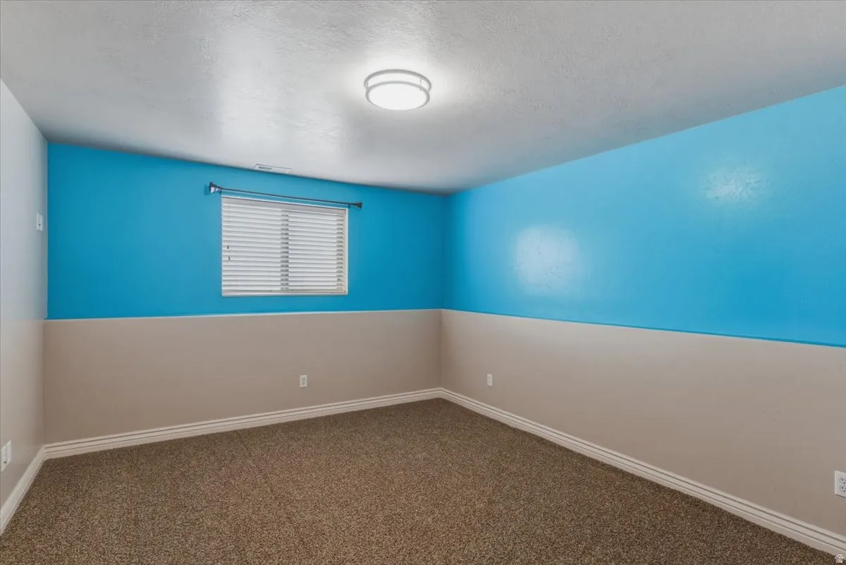 Spare room with dark colored carpet and a textured ceiling