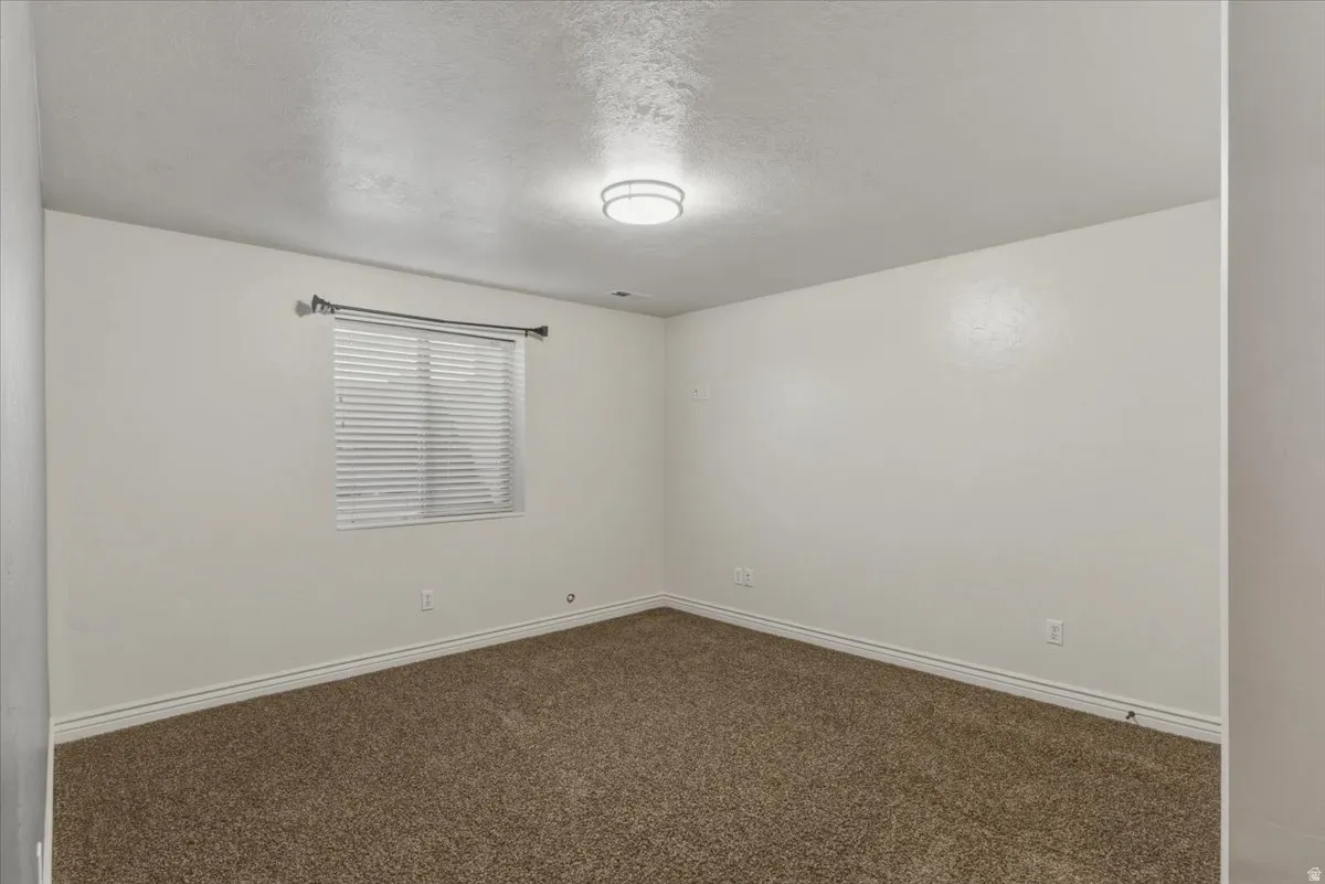Spare room featuring dark carpet and a textured ceiling