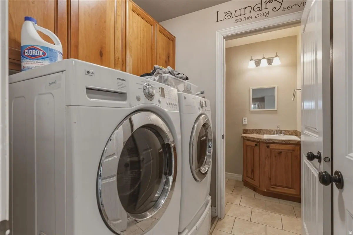 Laundry area with cabinet space, light tile patterned flooring, and separate washer and dryer
