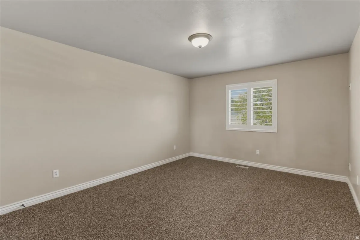 Unfurnished room featuring baseboards and dark carpet