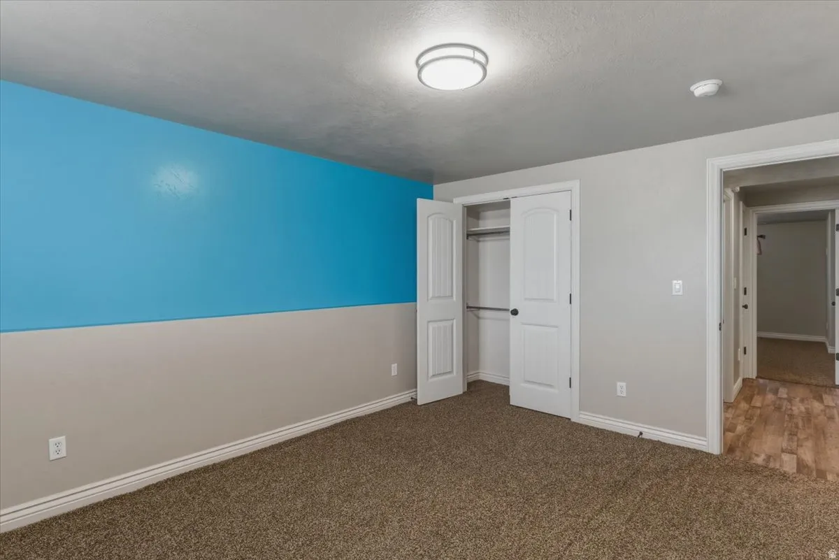 Unfurnished bedroom with a closet and dark carpet