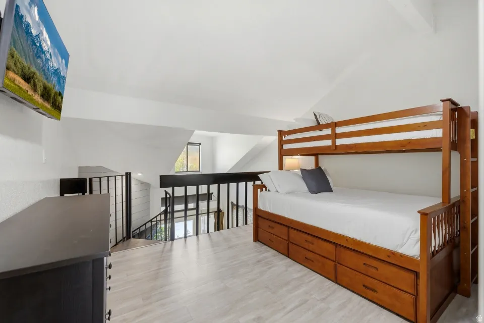 Bedroom with light wood-style flooring and lofted ceiling