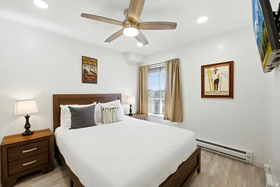 Bedroom with baseboard heating, light wood-style flooring, ceiling fan, and recessed lighting