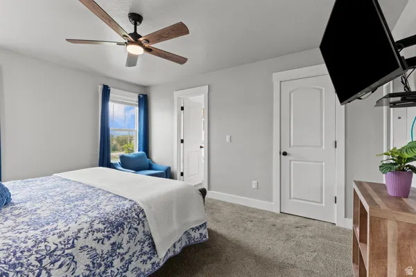 Carpeted bedroom with baseboards and a ceiling fan