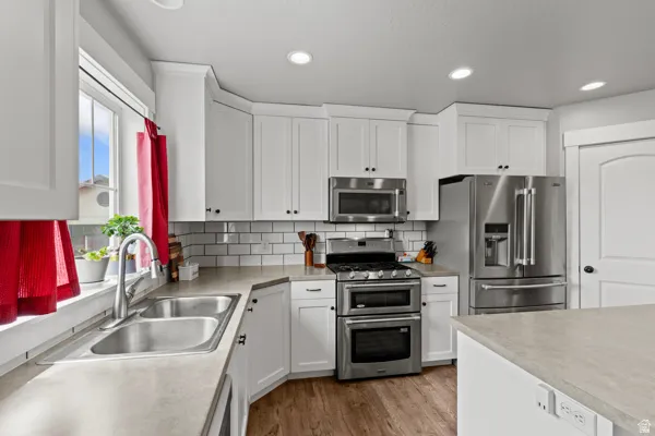 Kitchen with stainless steel appliances, white cabinets, dark wood finished floors, light countertops, and recessed lighting