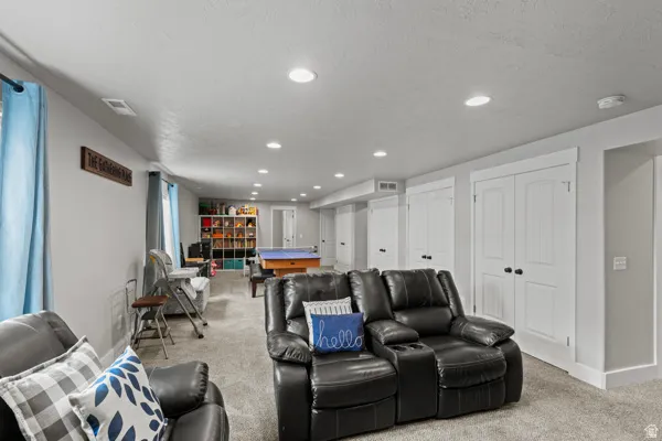 Home theater room with light carpet, recessed lighting, and a textured ceiling