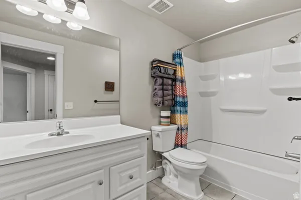 Bathroom with vanity, shower / bath combo with shower curtain, and light tile patterned flooring