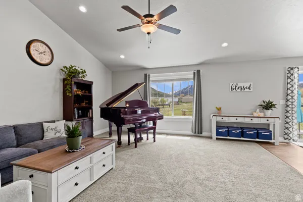Living room featuring light carpet, lofted ceiling, ceiling fan, and recessed lighting