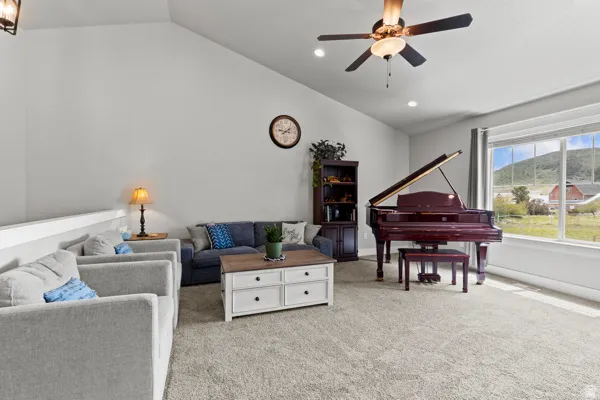 Carpeted living room featuring vaulted ceiling and a ceiling fan