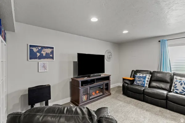 Living area featuring carpet floors, a textured ceiling, recessed lighting, and a fireplace