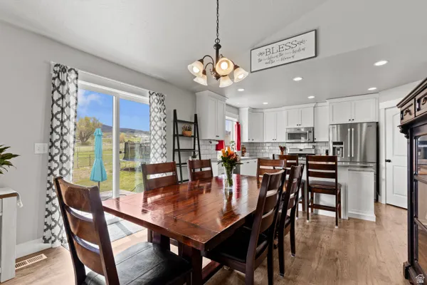 Dining area with a chandelier, light wood-style floors, and vaulted ceiling
