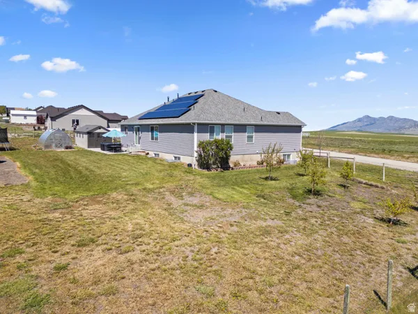 Rear view of property with roof mounted solar panels, an outdoor structure, and a mountain view